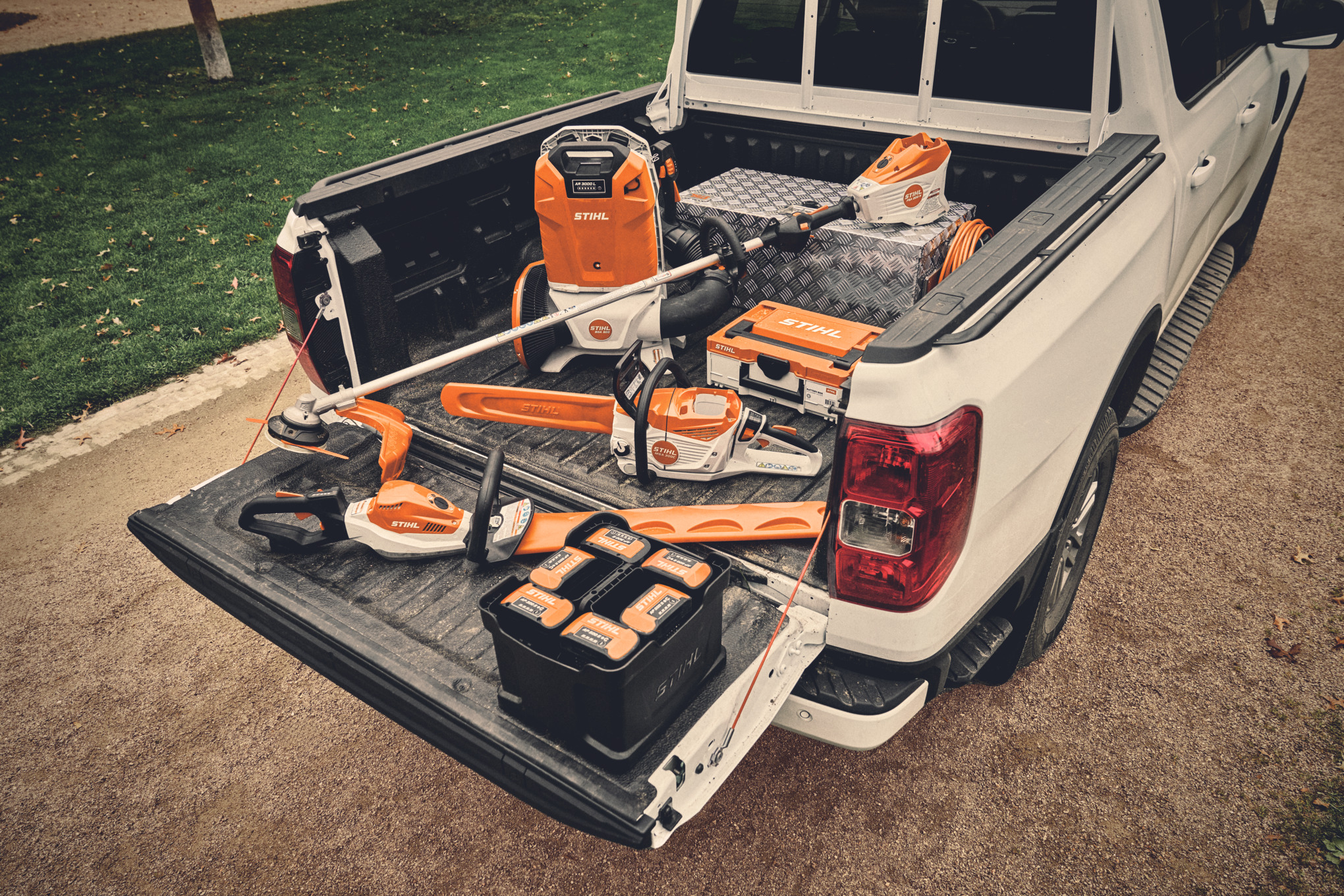 Vari utensili a batteria e batterie compatibili del sistema STIHL AP sul pianale di carico di un veicolo  
