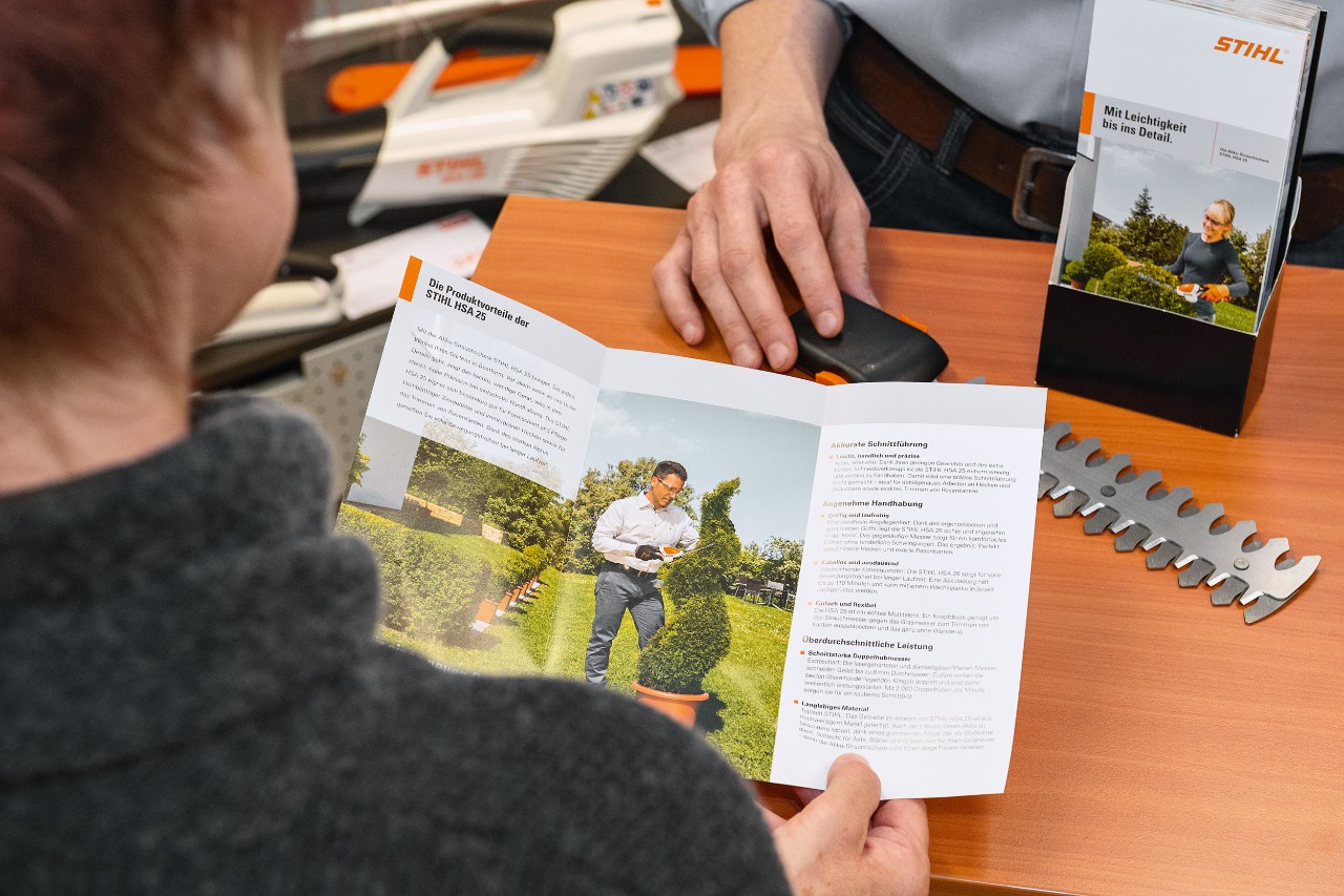 Una persona esamina i vantaggi del prodotto STIHL HSA 25 in una brochure
