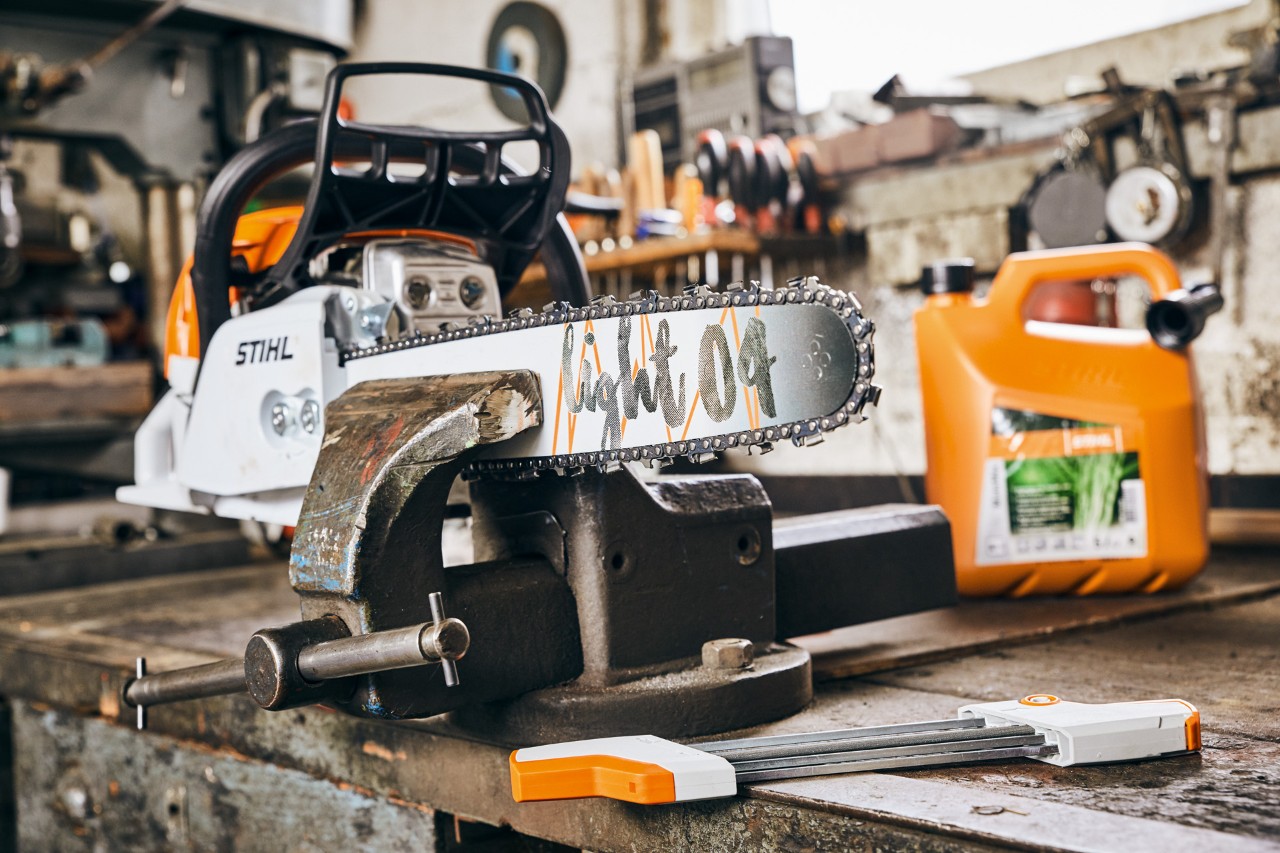 Motosega a benzina STIHL MS 261 C-M con spranga di guida Light 04 accanto alla miscela di carburante STIHL MotoMix prima dell'affilatura