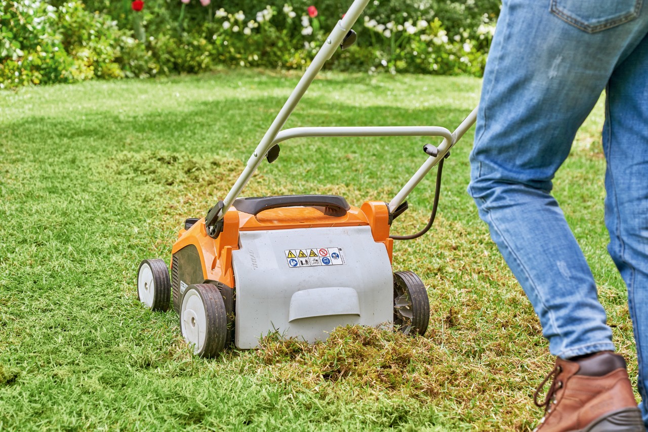 Persona che scava il prato con arieggiatore a batteria STIHL RLA 240 per rinnovare successivamente il prato