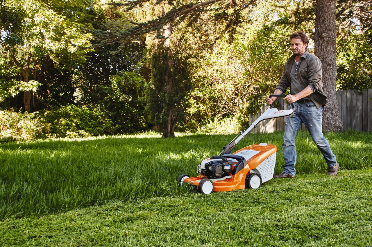 Un uomo taglia il prato in giardino con un tosaerba STIHL 