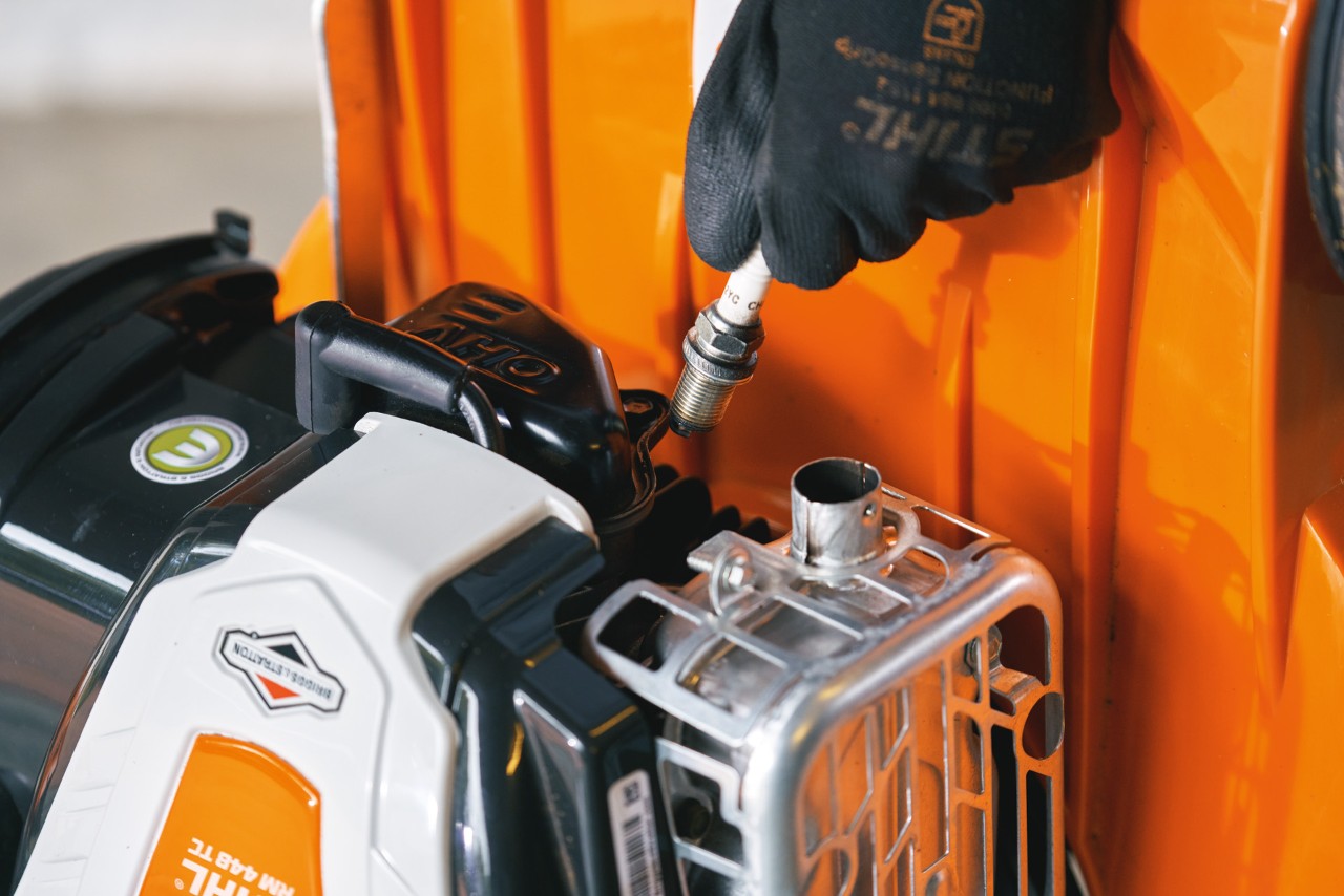 La candela di accensione viene rimossa dal motore del tosaerba a benzina STIHL RM 448 TC