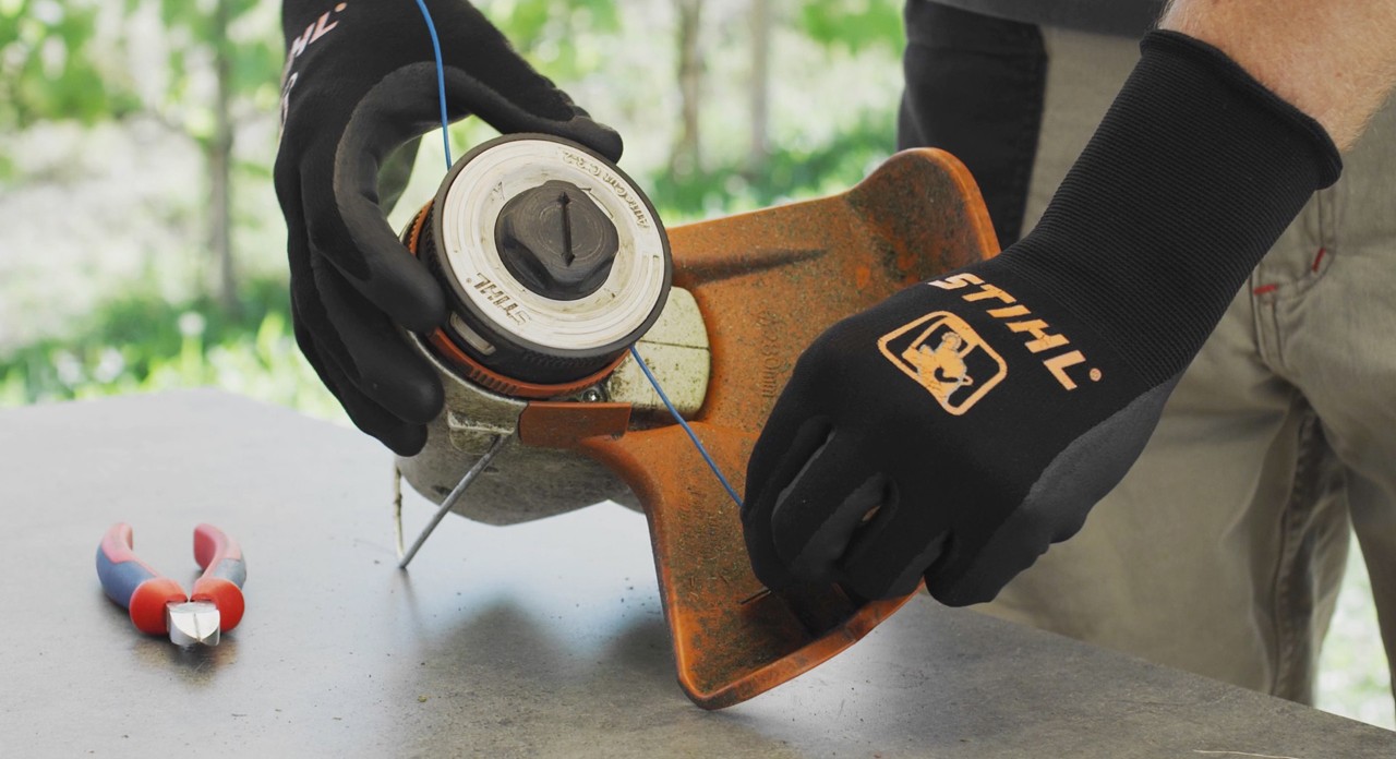 Persona che avvolge il filo di un decespugliatore a batteria STIHL FSA 57