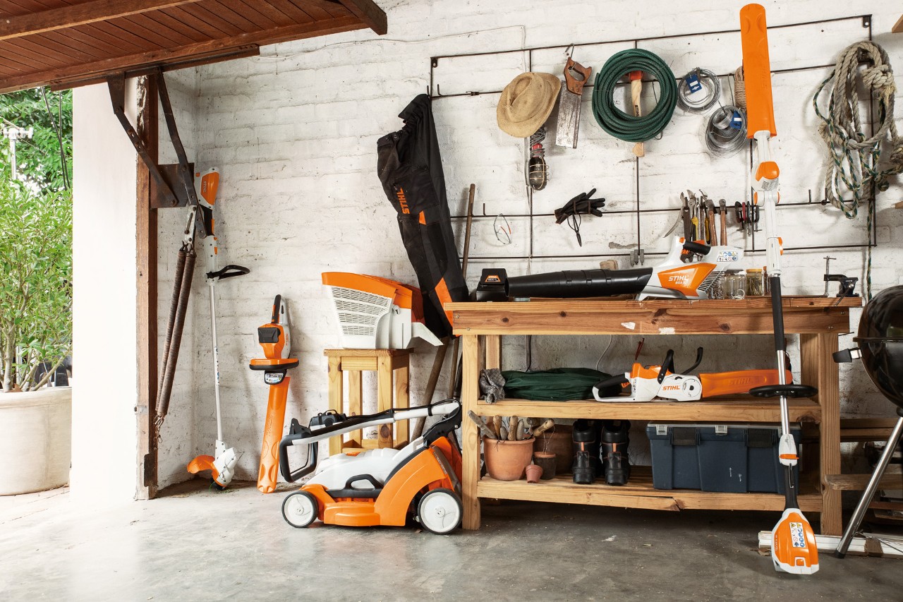 Il decespugliatore a batteria FSA 56 STIHL viene riposto appeso accanto al tagliasiepi a batteria HSA 56 e HLA 56 e al tosaerba a batteria RMA 339