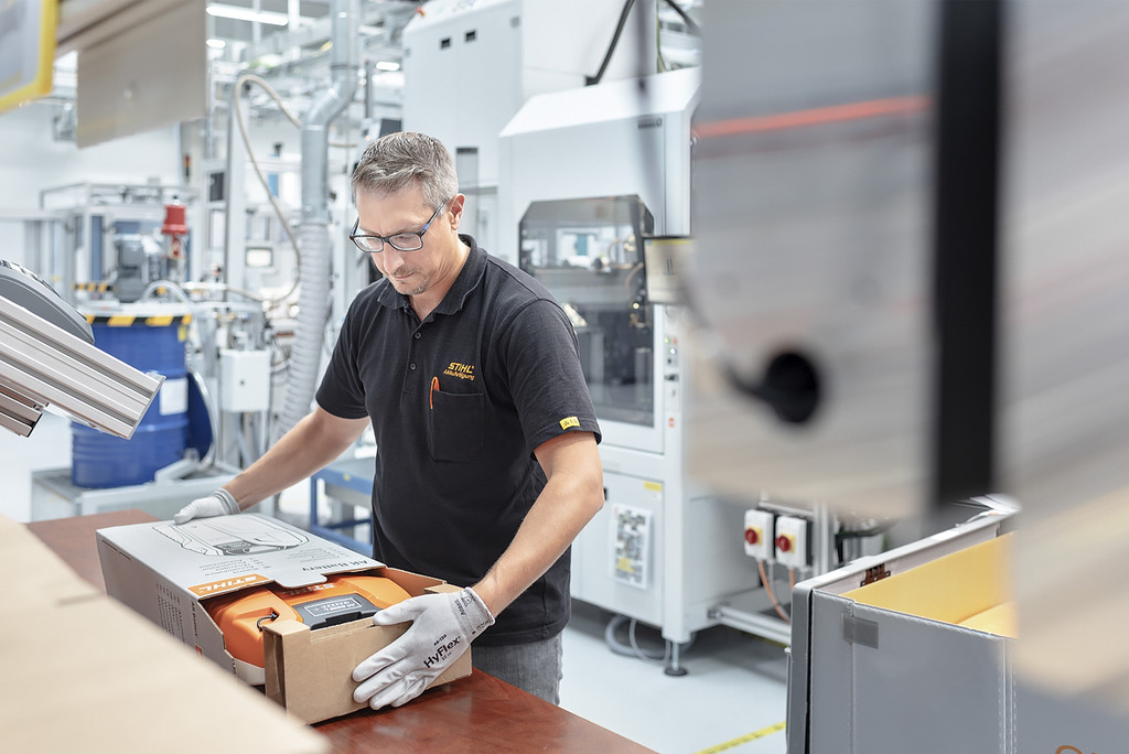 Un'addetta alla produzione di batterie imballa un utensile a batteria STIHL in una cassetta