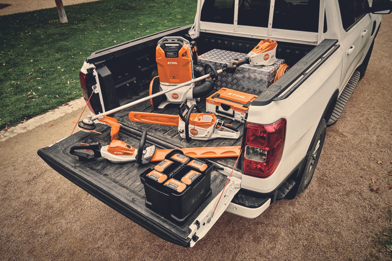 Diversi utensili a batteria del sistema STIHL AP e le relative batterie sulla superficie di carico di un veicolo
