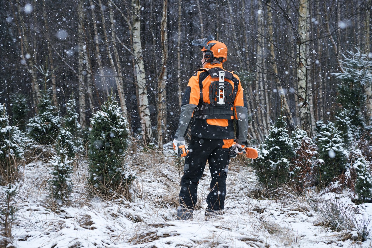 Addetto ai lavori forestali con DPI resistenti alle intemperie in un'area boschiva innevata
