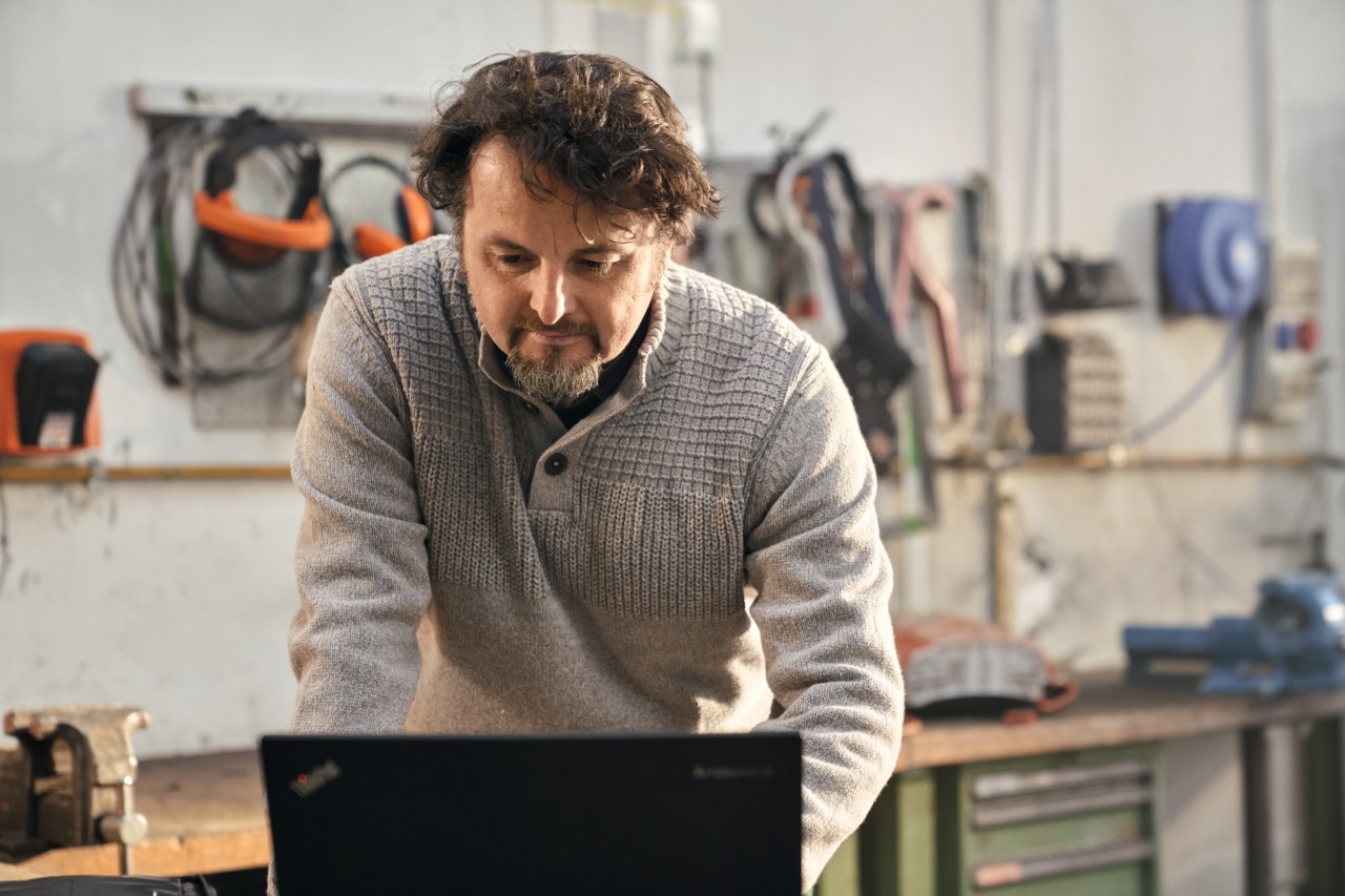 Uomo che utilizza un laptop all'interno di un'officina.